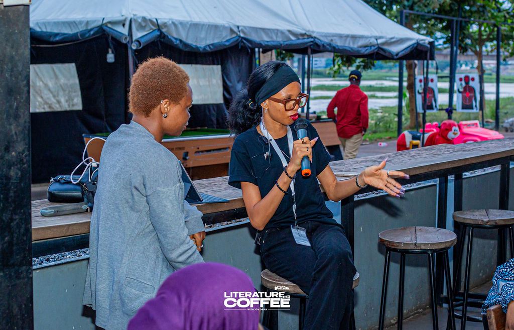 Stephanie holding a microphone, leading a conversation outdoors at a café venue.